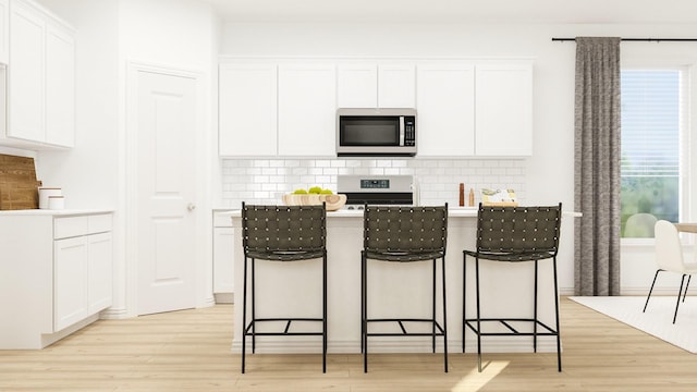 kitchen featuring stainless steel appliances, backsplash, white cabinets, and light hardwood / wood-style floors