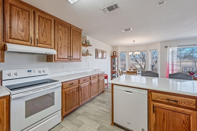 kitchen featuring hanging light fixtures, a textured ceiling, a notable chandelier, and white appliances