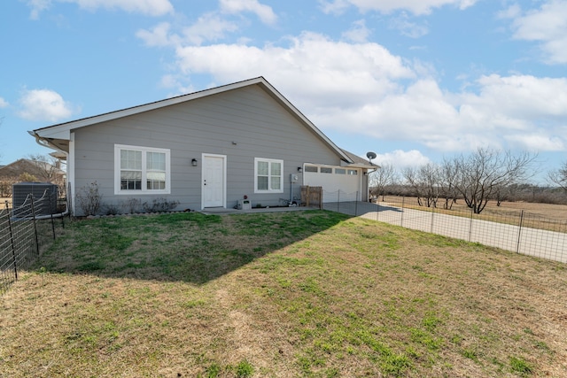 rear view of house featuring a garage, a yard, and central AC unit