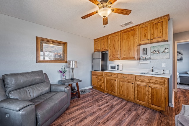 kitchen featuring stainless steel refrigerator, ceiling fan, dark hardwood / wood-style floors, and a textured ceiling