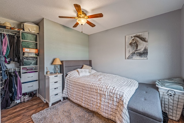 bedroom with dark hardwood / wood-style flooring, a textured ceiling, a closet, and ceiling fan