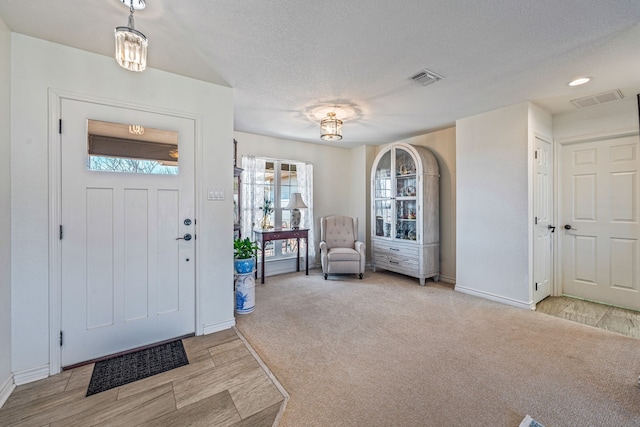 carpeted foyer with a textured ceiling