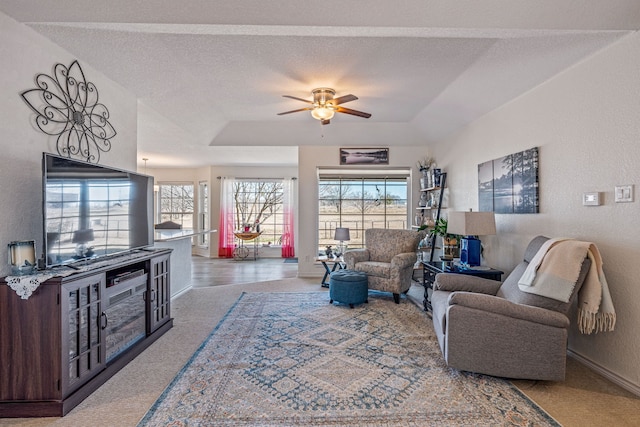 carpeted living room featuring ceiling fan, a raised ceiling, and a textured ceiling