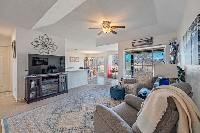 living room with ceiling fan, a textured ceiling, and a tray ceiling