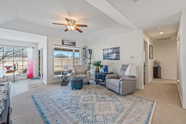 living room featuring plenty of natural light, light carpet, a textured ceiling, and a tray ceiling