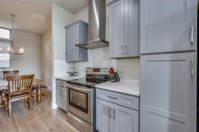 kitchen with electric range, pendant lighting, light hardwood / wood-style floors, decorative backsplash, and wall chimney range hood