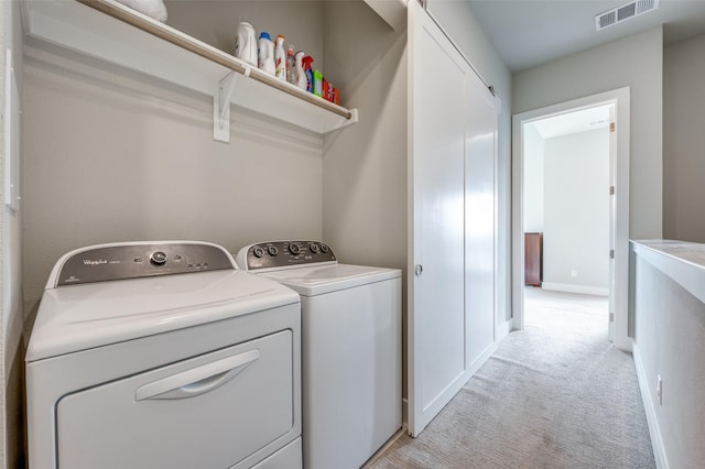 laundry area featuring light carpet and washer and clothes dryer