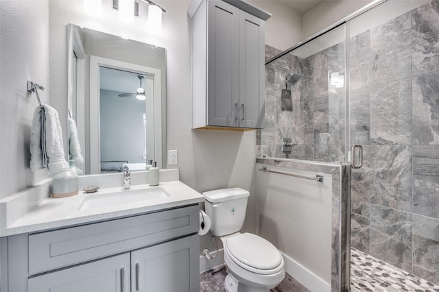 bathroom featuring vanity, ceiling fan, a shower with door, and toilet