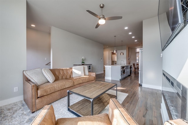 living room featuring dark hardwood / wood-style floors, sink, and ceiling fan