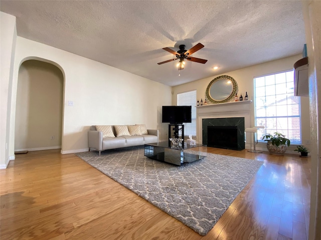 living room with hardwood / wood-style flooring, a fireplace, a textured ceiling, and ceiling fan