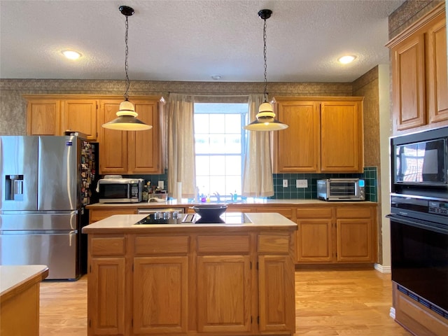 kitchen featuring pendant lighting, a center island, light hardwood / wood-style floors, black appliances, and a textured ceiling