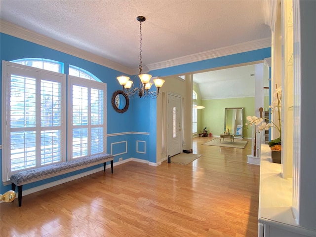 dining space with a notable chandelier, crown molding, a textured ceiling, and light wood-type flooring