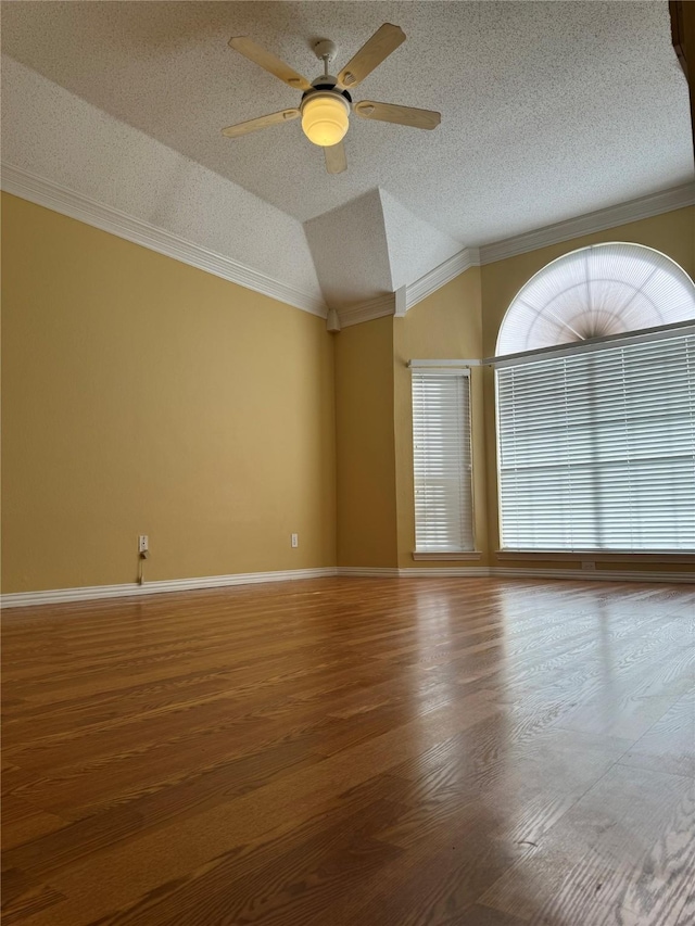 empty room featuring ceiling fan, hardwood / wood-style floors, ornamental molding, a textured ceiling, and vaulted ceiling