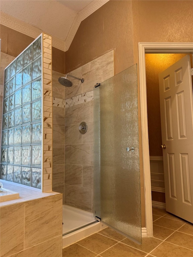 bathroom with vaulted ceiling, a tile shower, and tile patterned floors