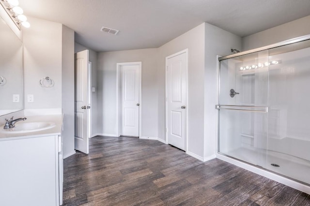 bathroom with wood-type flooring, an enclosed shower, and vanity