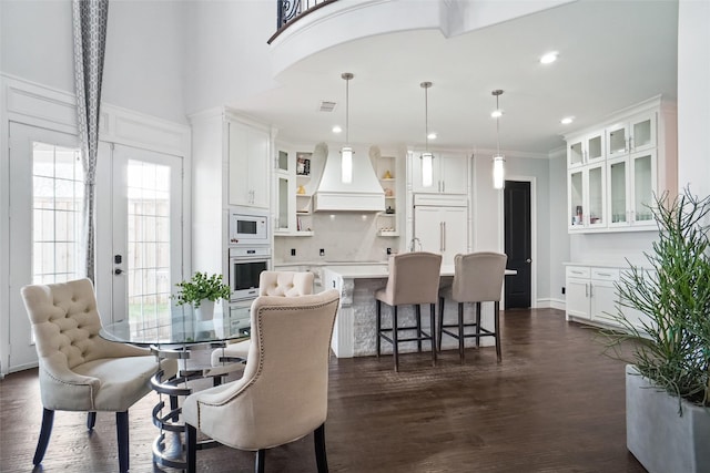 dining room featuring ornamental molding, a towering ceiling, and dark hardwood / wood-style flooring