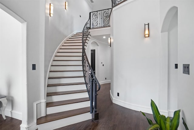 stairway featuring wood-type flooring and a high ceiling