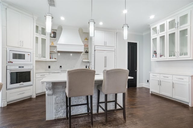 kitchen featuring white cabinetry, built in appliances, and custom exhaust hood