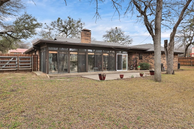 rear view of house featuring a patio, a sunroom, a chimney, fence, and a yard