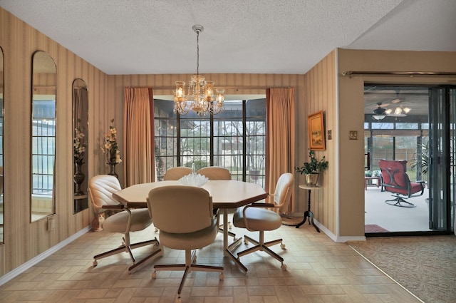 dining room with a textured ceiling, a notable chandelier, and wooden walls