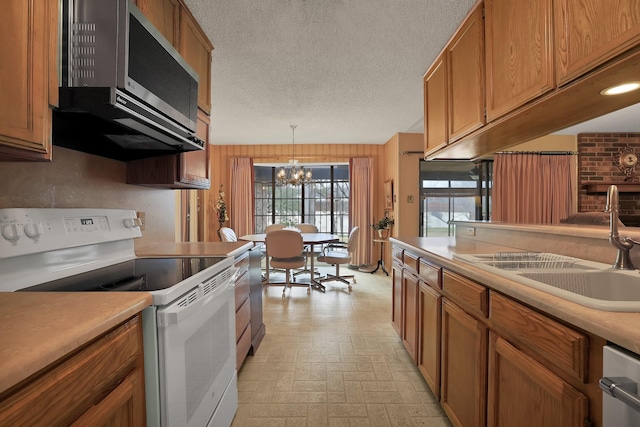 kitchen with pendant lighting, sink, appliances with stainless steel finishes, a chandelier, and wood walls