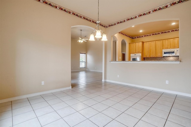 interior space featuring pendant lighting, light tile patterned floors, white appliances, ceiling fan with notable chandelier, and light brown cabinets