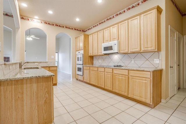 kitchen with light brown cabinets, white appliances, and kitchen peninsula