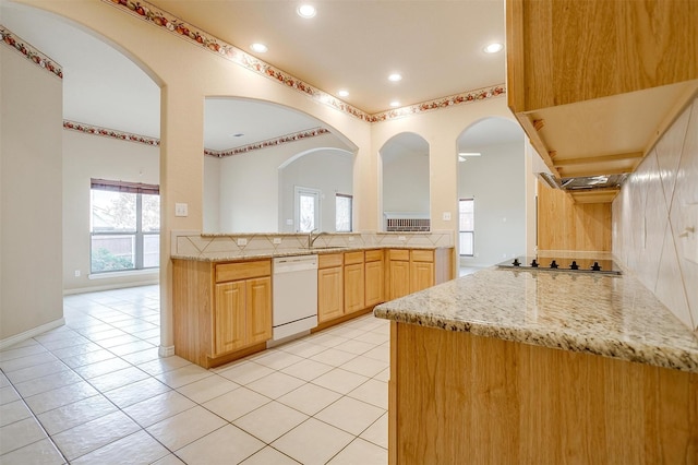 kitchen with light brown cabinetry, dishwasher, sink, light stone counters, and black electric cooktop