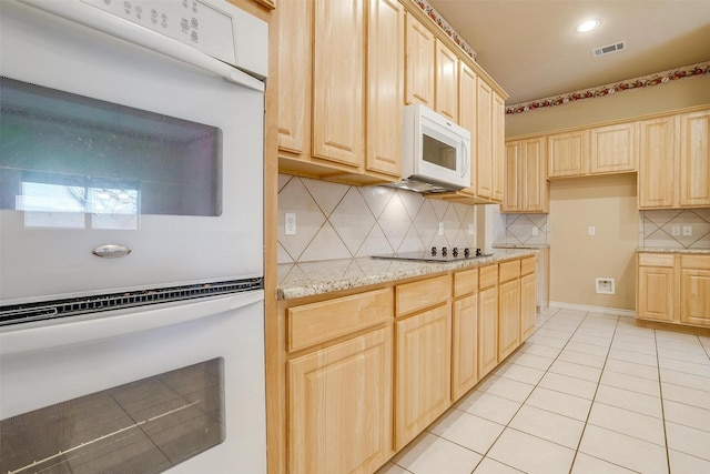 kitchen with light tile patterned floors, white appliances, light stone counters, decorative backsplash, and light brown cabinets