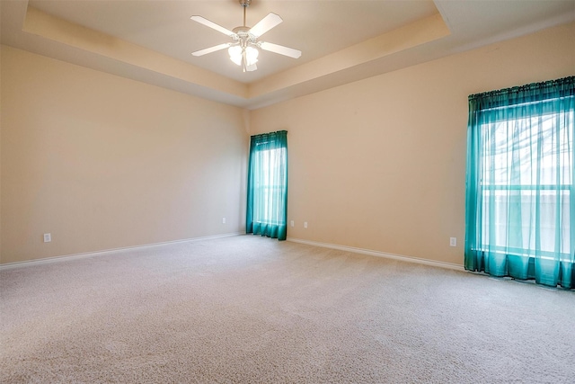 empty room featuring ceiling fan, carpet flooring, and a tray ceiling