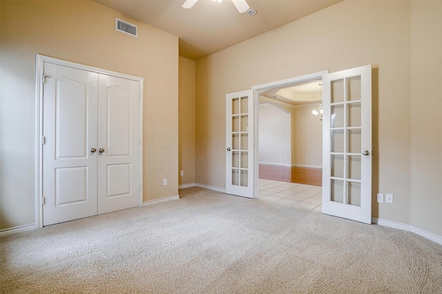 unfurnished bedroom featuring a closet, light colored carpet, french doors, and ceiling fan