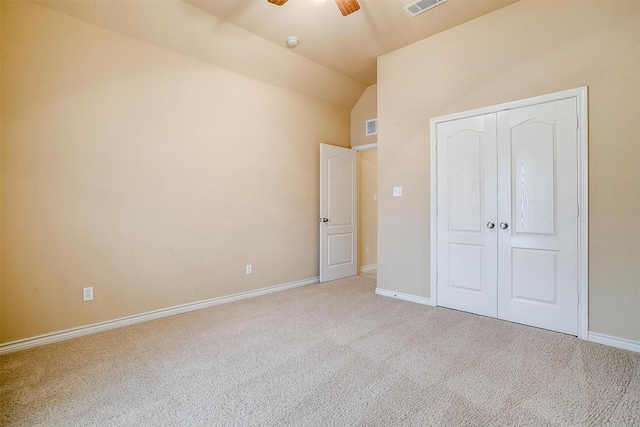 unfurnished bedroom with ceiling fan, a closet, lofted ceiling, and light carpet