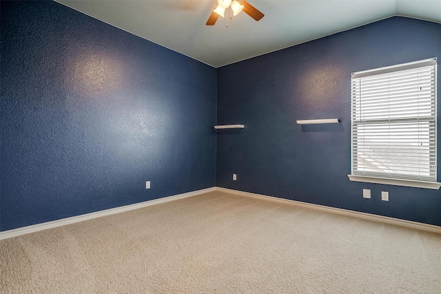 carpeted spare room featuring vaulted ceiling and ceiling fan