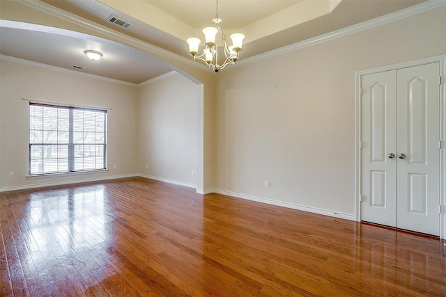 unfurnished room featuring ornamental molding, wood-type flooring, a chandelier, and a raised ceiling