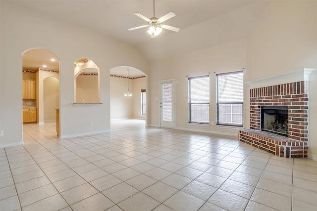 unfurnished living room with light tile patterned flooring, ceiling fan, a fireplace, and high vaulted ceiling