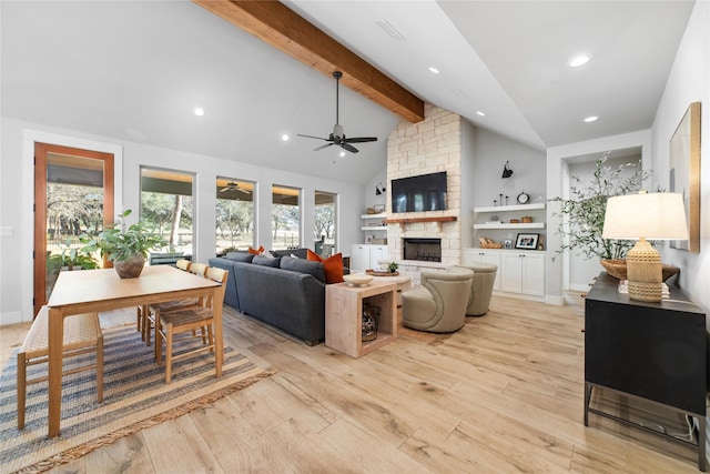 living room with ceiling fan, a fireplace, beam ceiling, and light hardwood / wood-style flooring