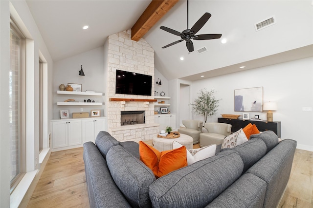 living room featuring beamed ceiling, ceiling fan, a fireplace, and light hardwood / wood-style flooring