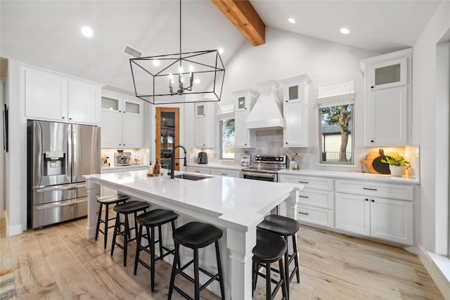 kitchen with sink, premium range hood, white cabinetry, a kitchen island with sink, and stainless steel appliances