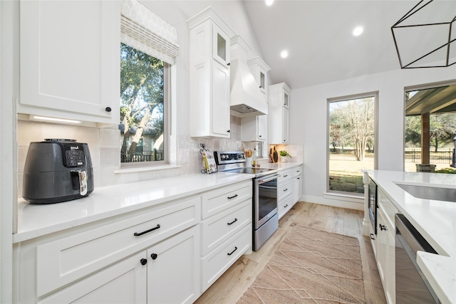 kitchen with sink, appliances with stainless steel finishes, white cabinetry, hanging light fixtures, and backsplash