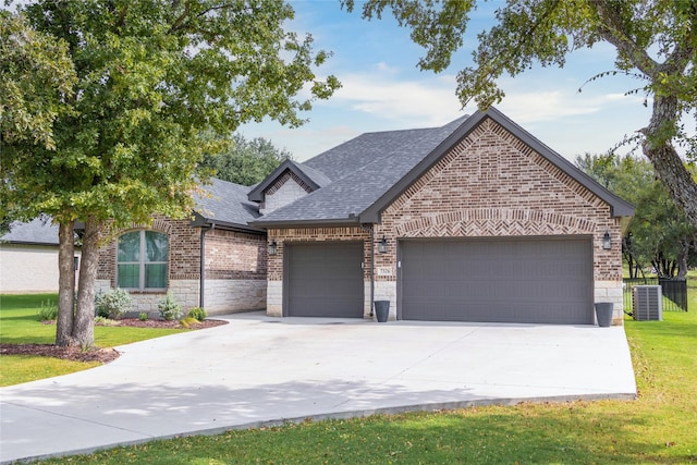 view of front facade with a garage, central AC, and a front lawn