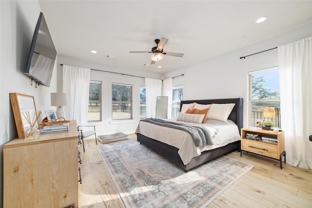 bedroom with ceiling fan, multiple windows, and light wood-type flooring