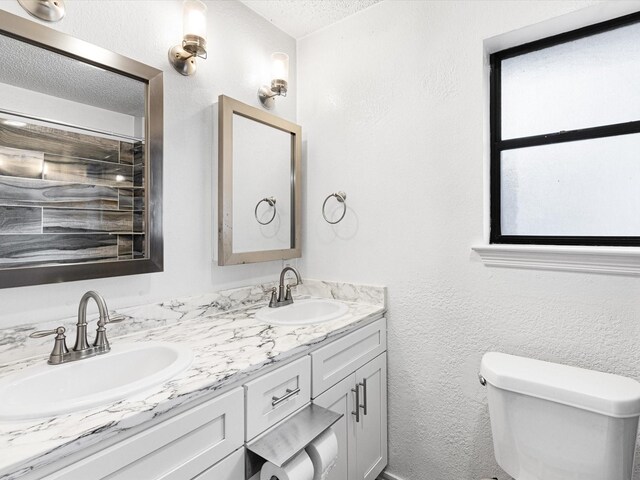 bathroom with vanity, tiled shower, and toilet