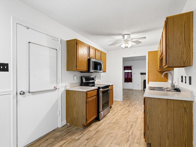 kitchen with sink, ceiling fan, stainless steel appliances, a textured ceiling, and light wood-type flooring