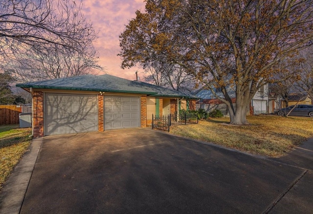 ranch-style home with a garage and a lawn