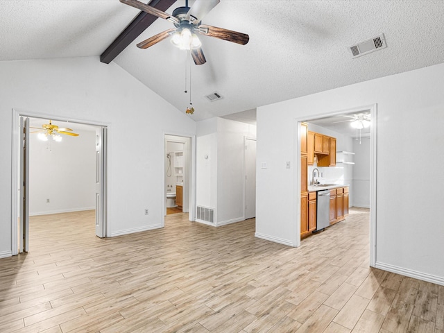 unfurnished living room featuring sink, vaulted ceiling with beams, a textured ceiling, and light hardwood / wood-style floors