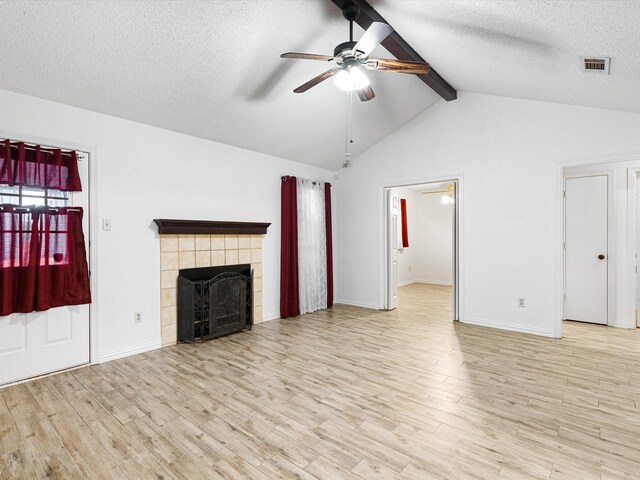 unfurnished living room with lofted ceiling with beams, a textured ceiling, ceiling fan, a fireplace, and light hardwood / wood-style floors