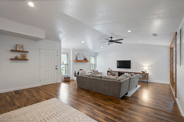 living room with vaulted ceiling, a fireplace, ceiling fan, dark wood-type flooring, and a textured ceiling