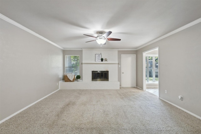 unfurnished living room featuring crown molding, light colored carpet, ceiling fan, and a brick fireplace