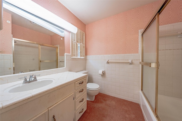 full bathroom with a wainscoted wall, shower / bath combination with glass door, toilet, vanity, and wallpapered walls