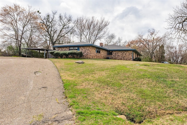 view of front of house featuring a chimney, a front lawn, aphalt driveway, and a carport